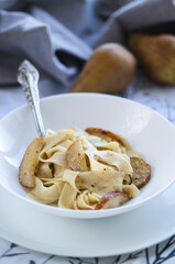 Dish featuring pasta, pears, and spoon, with a creamy bchamel sauce