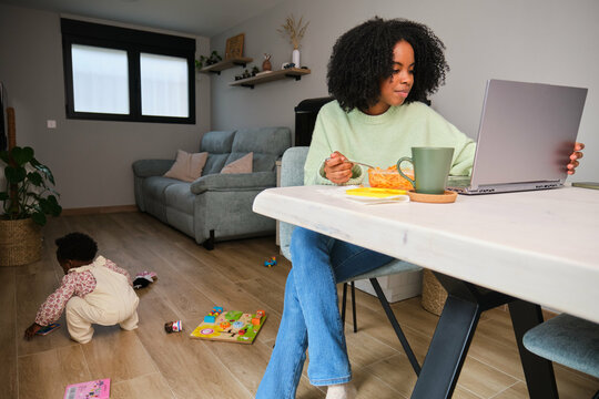 Cuban mother eating, working a taking care of her toddler daughter.