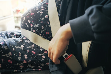 Pregnant woman wearing seat belt before driving a car