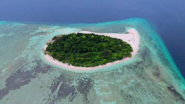 Aerial shot of the small Mantigue Island, covered with trees, in the Philippines.