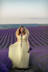 Woman poses in lavender field. Happy woman in yellow dress holds lavender bouquet. Aromatherapy...