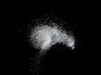 Spilled white sea salt on a black background. clear crystalline pebbles on a black background. Salt explosion.