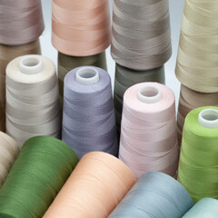 Thread spools background. Various colors sewing kit. Collection of threads. Pale pastel colors. Sew...