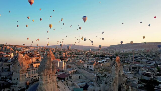 Aerial view of colorful hot air balloons in Cappadocia, Turkey, fly in the sky over a mountain valley at summer sunrise. The vibrant balloons rise gracefully over the valley, Goreme