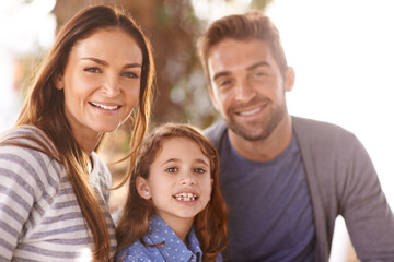 Happy family, portrait and smile in park by trees, sunshine and outdoor on vacation, bonding and relax. Father, mother and daughter in nature for summer, together and holiday with connection for love
