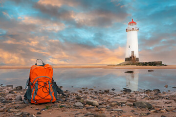 Orange rucksack on the seaside against the sea and lighthouse in fantastic weather. Travel...