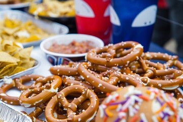 a table at a sporting event concession stand with pretzels and nachos