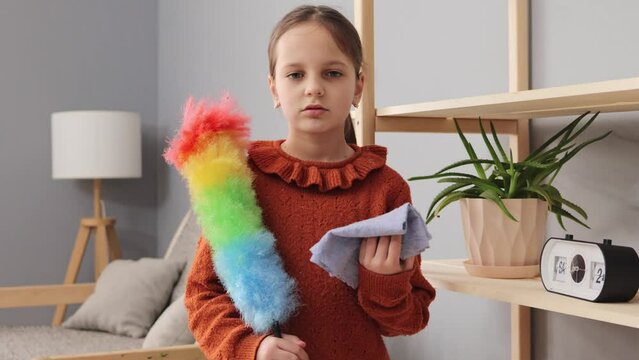 Child aiding in cleaning. Girl assisting with chores. Domestic cleaning routine. Housework with children. Little girl holding pp duster helping her mother with wiping dust