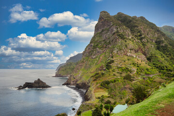 The view of the Madeira coastline, where the vast ocean meets towering cliffs under a sky adorned...