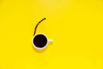 Cup of coffee and coffee bean on a yellow background, with space for copy text