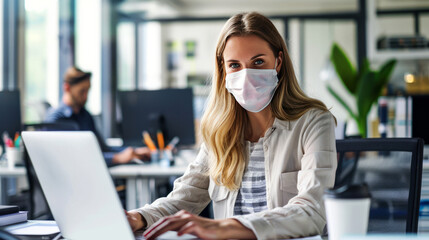 Focused young professional woman wearing a mask while working remotely in a modern office setting