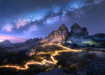 Milky Way, car light trails on mountain road at starry night