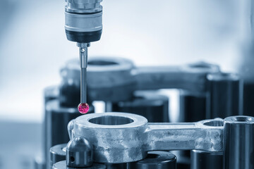 The  CMM probe measuring the  automotive parts in the light blue scene.