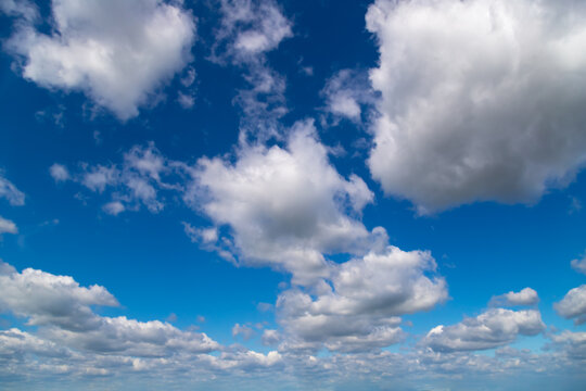 White cumulus clouds on a clear blue sky.