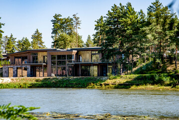 Fototapeta na wymiar old wooden and stone house with flowers in the garden on summer sunny day on the river