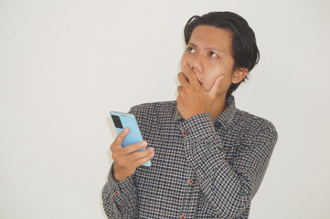 Young Asian man thinking about something while holding mobile phone. isolated white background