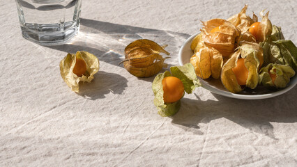 Healthy vitamin berry eating concept, physalis fruits and glass with water in natural bright...