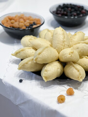 Varenyki in of dishes on a table with bowls in the background