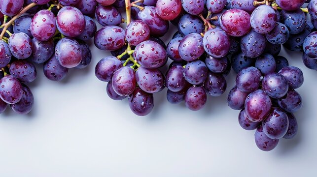 Fresh purple grapes with water droplets on a white background, top view with copy space.