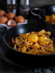 A staple food dish of lasagnette pasta with eggs and bacon on a table