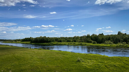 River bank, blue sky and lush green grass on a sunny summer day. - 768573769