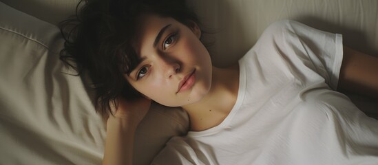 A person with a short haircut, wearing a white shirt, is lying in bed. The individual appears relaxed and comfortable in their home setting, possibly during a holiday period.