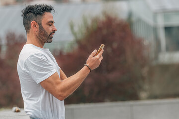 portrait of attractive man with beard outdoors looking at mobile phone