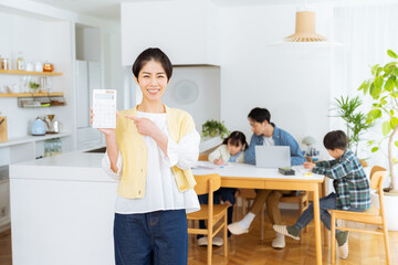 Obraz premium ダイニングルームで計算機を持つ主婦