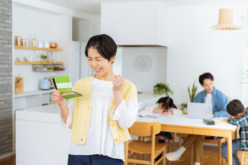 ダイニングルームで通帳を持つ主婦