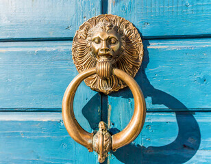 Bronze knock handle door knocker on a blue wooden door