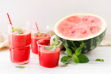 Glass of fresh watermelon smoothie covered with mint leaves.