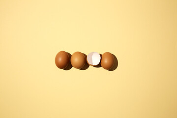 3 organic eggs and one cracked on a yellow background,
hatched chick, cracked eggshell, easter concept