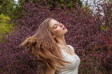 Excited fashion model with long brown hair and natural makeup against floral background outdoor - 768591908