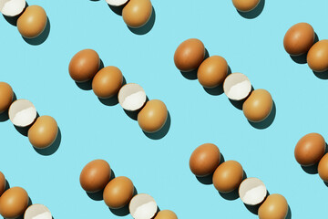 Egg pattern, raw chicken eggs on a blue background with broken eggs. Top view, hatched chick, cracked eggshell, easter concept