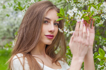 Attractive fashion model with long brown hair and natural makeup against floral background outdoor - 768591943