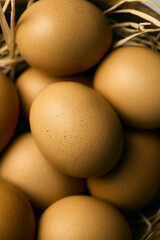 Raw eggs in a deep brown bowl on a straw pillow, top view, close up