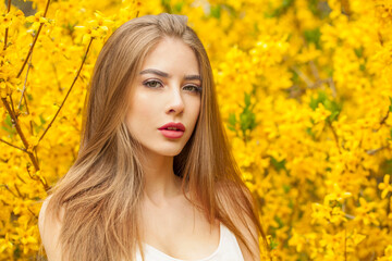 Posing fashion model with long brown hair and natural makeup against floral background outdoor - 768593126