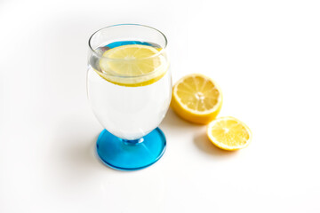 Lemon water in a glass and half a lemon on a white background. Photo