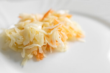 Salad with cabbage and carrots on a white plate, table. Photo