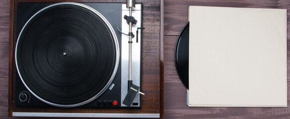close-up of a vinyl record player, on a wooden table, there is a place for an inscription on the cardboard packaging