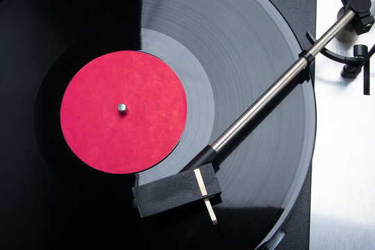 a black vinyl record lies on the player to play music