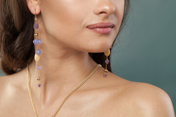 Gold necklace and long earring with blue and purple chalcedony and amethyst stones and pearl on jewelry model closeup - 768594530