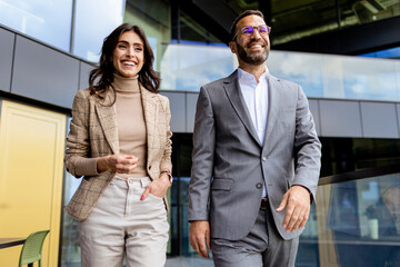 Cheerful Colleagues Exiting a Modern Office Building on a Bright Afternoon - 768596926