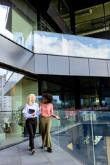 Two Professional Women Sharing a Joyful Conversation at a Modern Office Building - 768597177