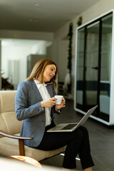 Elegant professional woman engaged in a business call with morning coffee - 768598529