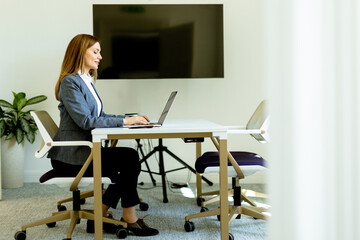 Business woman engrossed in work, sitting at a desk and using a laptop computer. - 768598535