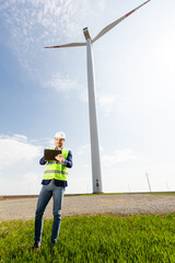 Engineer Inspecting Wind Turbine Efficiency in Vast Green Field on a Sunny Day. - 768598929