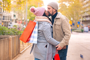 A young couple in love returns carrying shopping bags, the husband kisses his wife