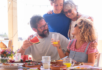 Cheerful multi generation family hugging each other in outdoors enjoying brunch together. Senior...