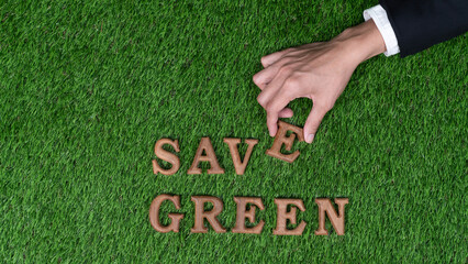 Hand arrange wooden alphabet in ECO awareness campaign design on biophilia green grass background...